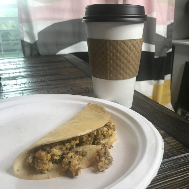 Keto Crepe filled with sausage egg and cheese sitting on a table with coffee