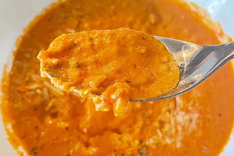 Photo of warm keto tomato soup in a bowl being eaten with a spoon